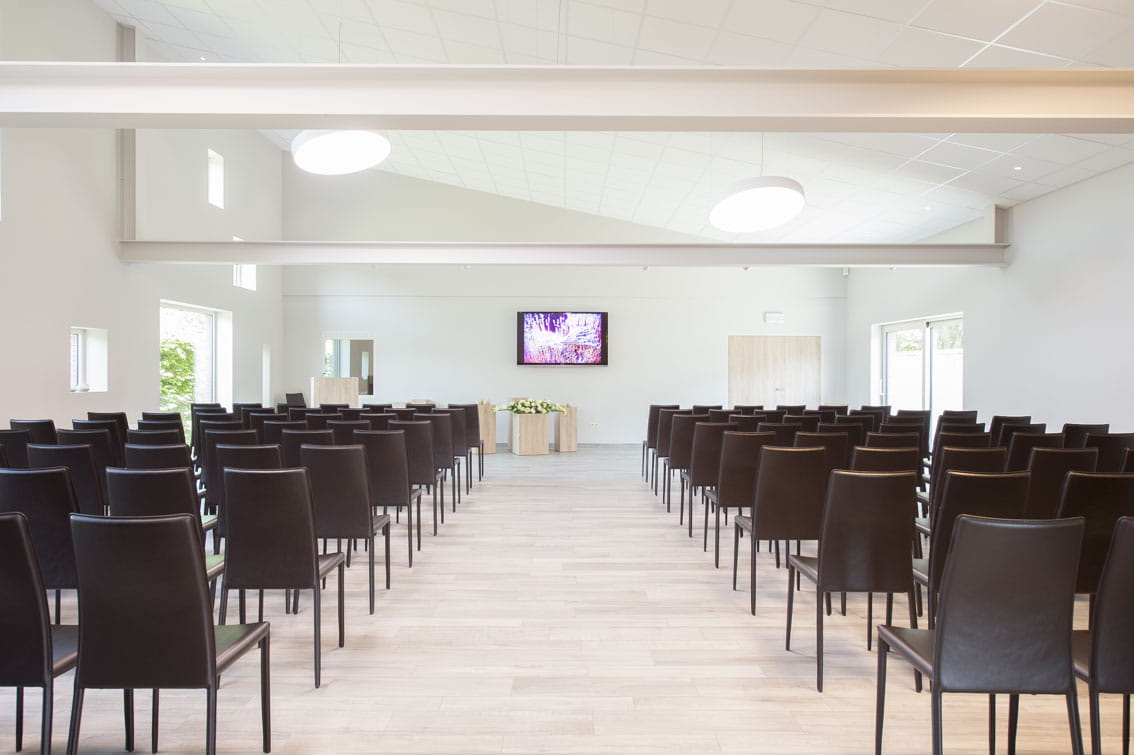 Aula met zwarte stoelen en een middenpad